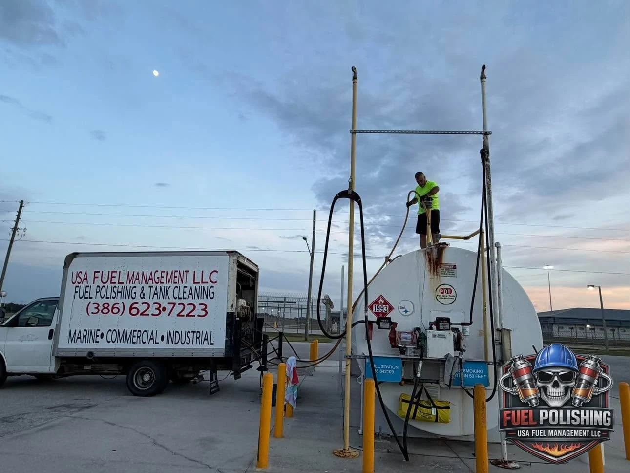 A worker servicing a large storage tank at sunset beside a USA Fuel Management truck